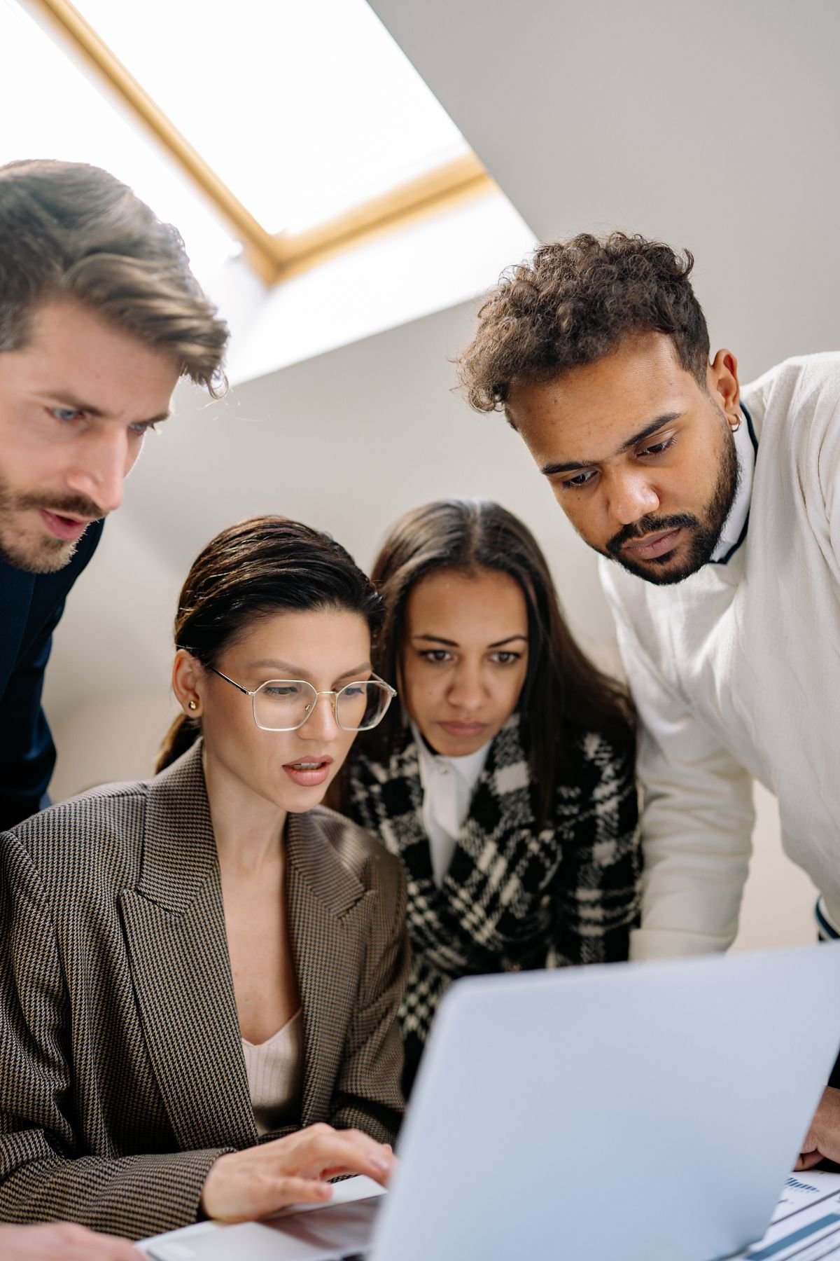 A diverse group of professionals collaborating around a laptop at work